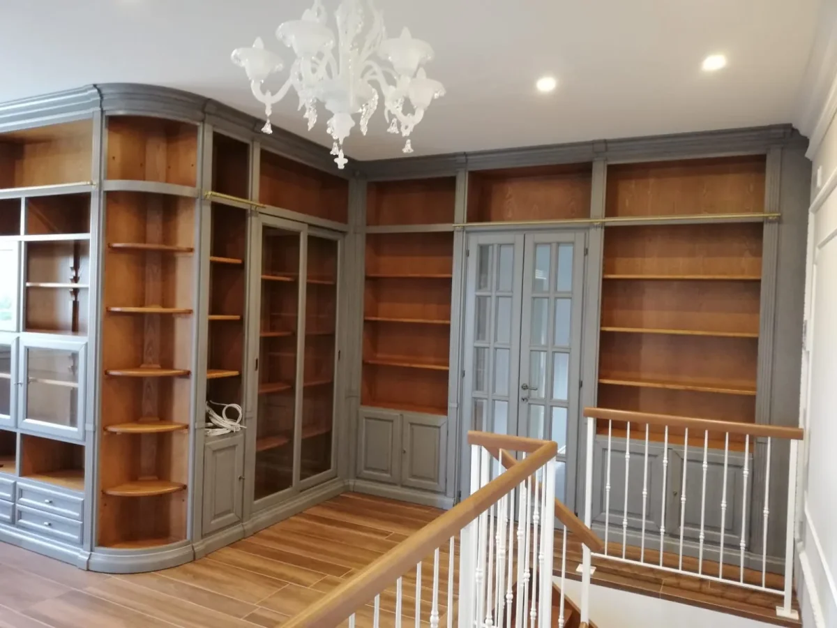 Angolo curvo della libreria con mensole sagomate in noce, ante a vetro e lampadario di Murano