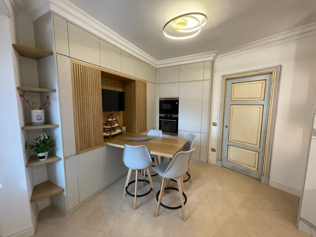 Zona pranzo con tavolo alto in rovere, sgabelli, boiserie doghata e mensole d'angolo