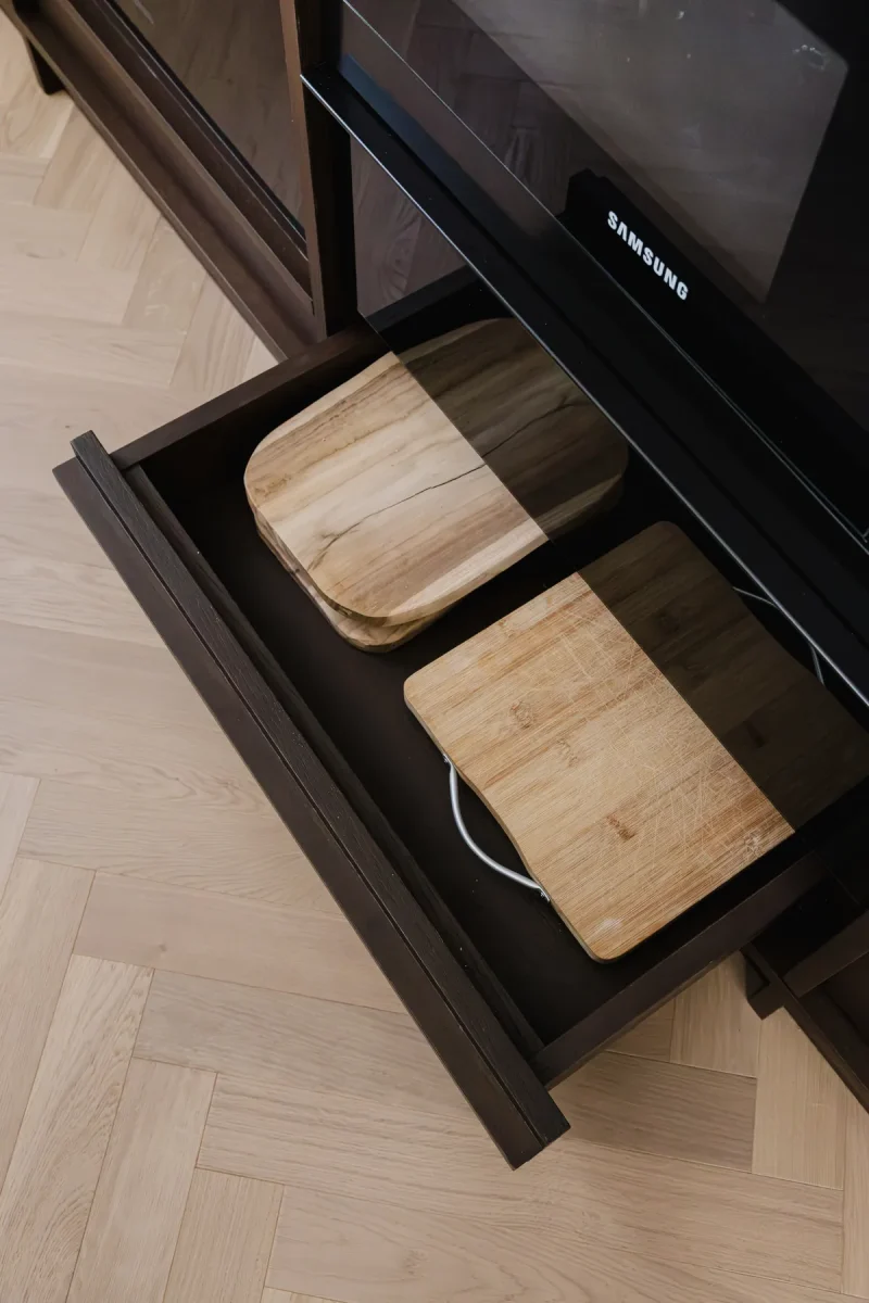 Cassetto aperto con taglieri in legno, sotto il piano in marmo verde alpi.